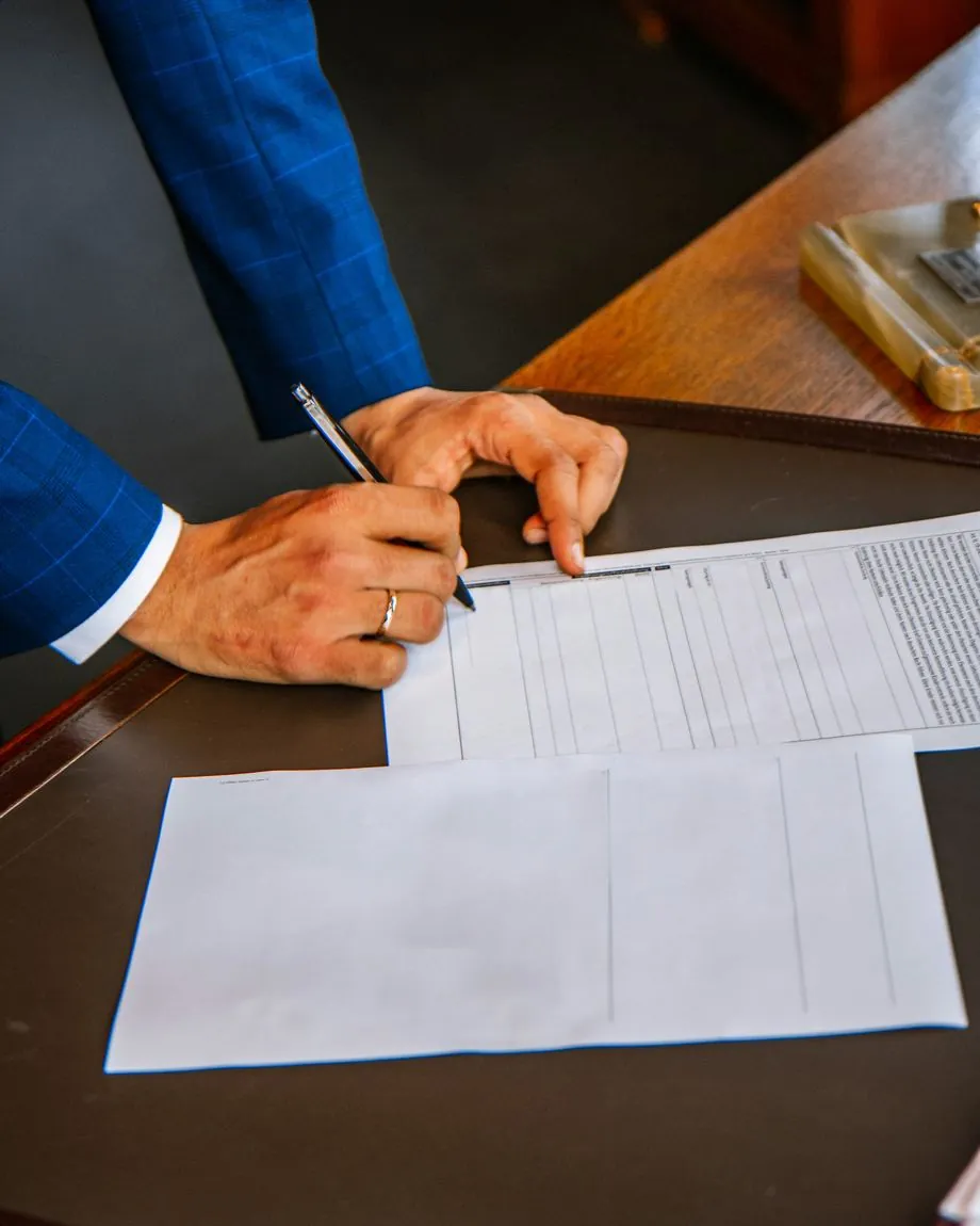 Persona revisando y firmando la documentación de una comunidad sobre un escritorio
